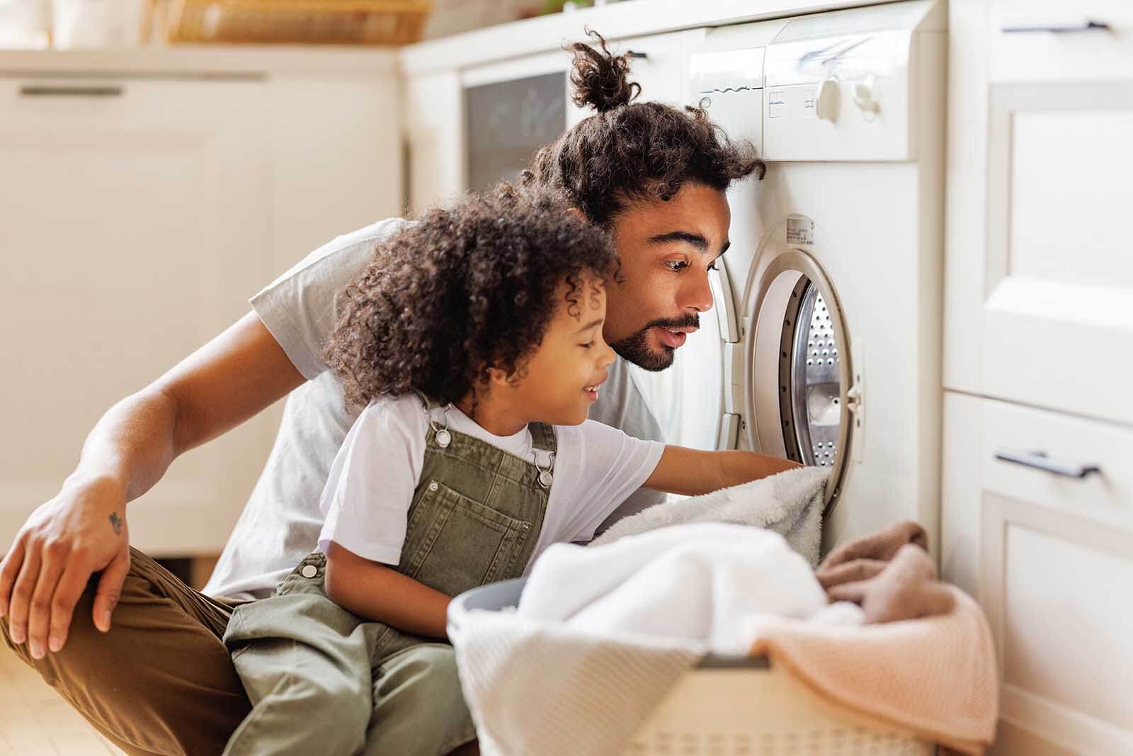 A dad doing laundry with his kid